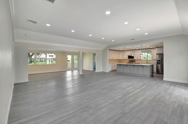 unfurnished living room with light hardwood / wood-style floors, crown molding, and french doors