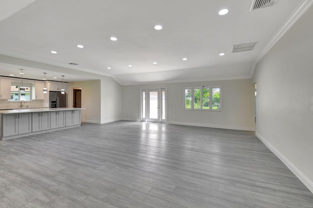 unfurnished living room featuring sink, crown molding, and light hardwood / wood-style flooring