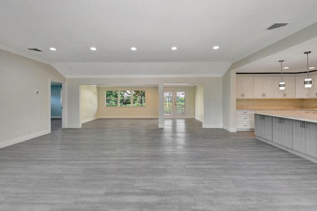 unfurnished living room with light hardwood / wood-style floors, french doors, ornamental molding, and vaulted ceiling