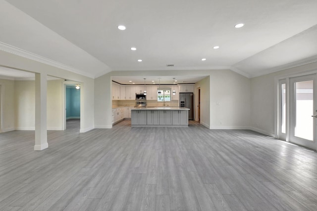 unfurnished living room featuring a wealth of natural light, vaulted ceiling, and light hardwood / wood-style flooring