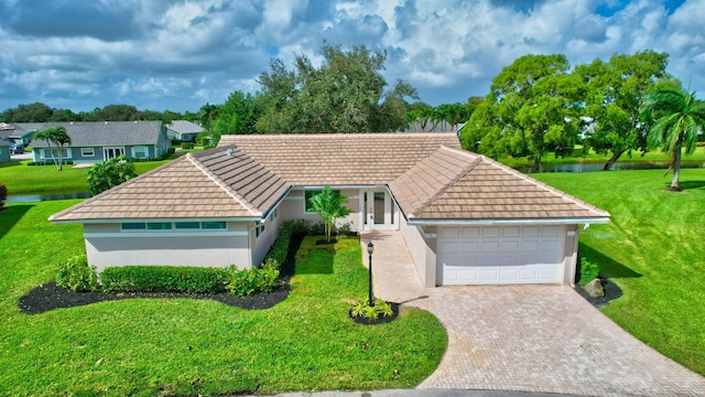 view of front of house featuring a front yard, a garage, and a water view