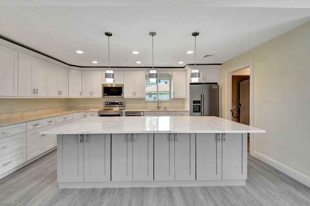 kitchen featuring stainless steel appliances, sink, pendant lighting, and a kitchen island