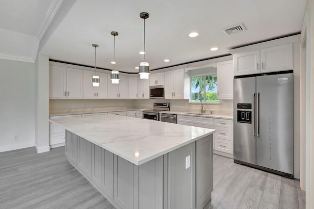 kitchen featuring stainless steel appliances, sink, pendant lighting, white cabinetry, and light hardwood / wood-style floors