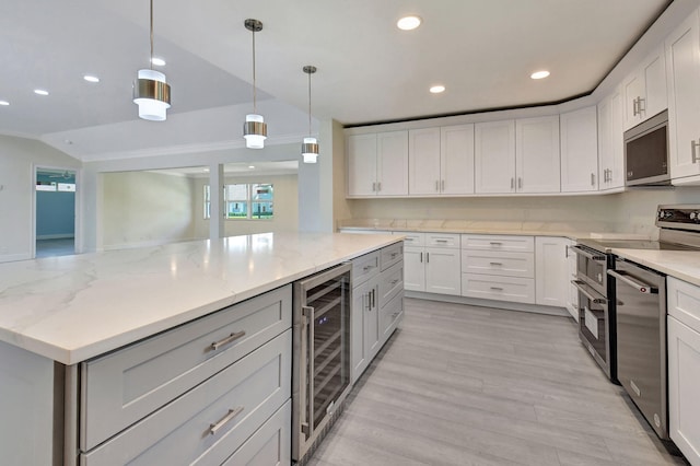 kitchen featuring appliances with stainless steel finishes, white cabinets, decorative light fixtures, and beverage cooler