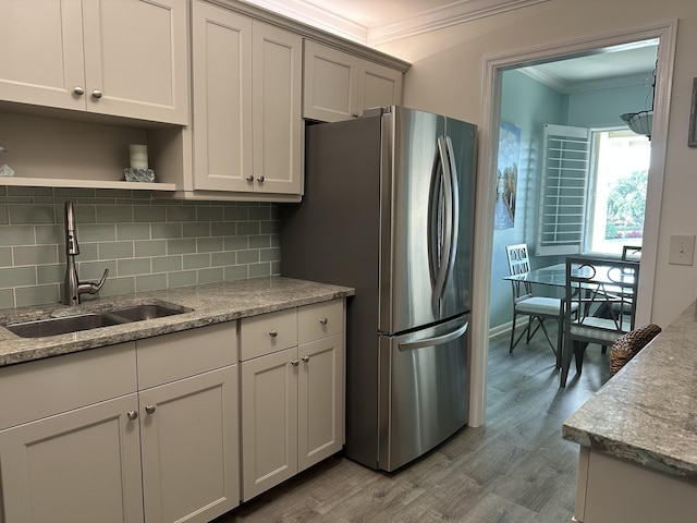 kitchen with backsplash, crown molding, sink, light hardwood / wood-style flooring, and stainless steel refrigerator