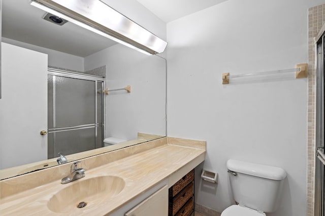 bathroom featuring vanity, a shower with shower door, and toilet