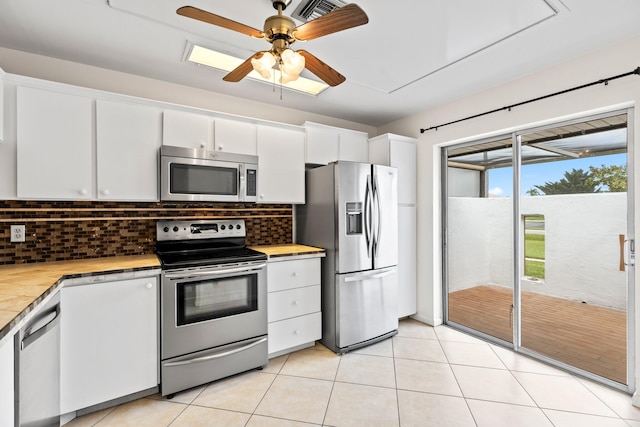 kitchen featuring decorative backsplash, white cabinets, stainless steel appliances, and ceiling fan