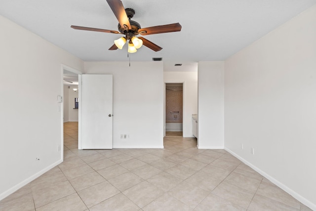 unfurnished bedroom featuring a spacious closet, light tile patterned flooring, and ceiling fan