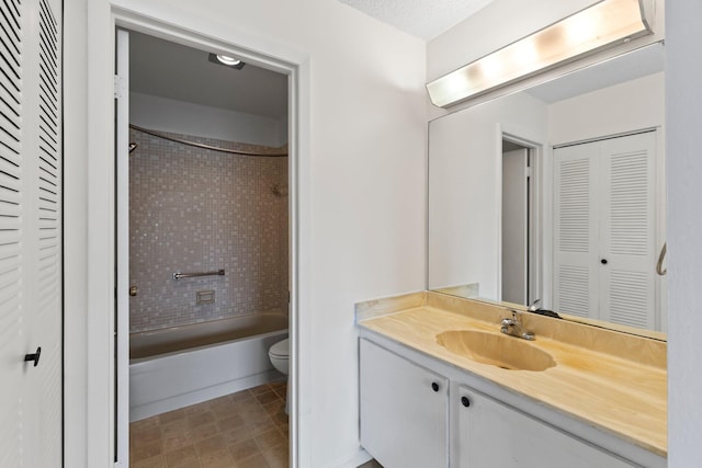 full bathroom featuring vanity, tiled shower / bath combo, and toilet