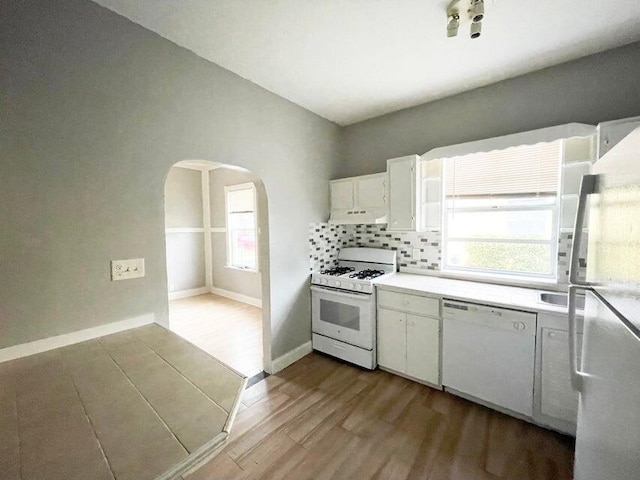 kitchen with white appliances, backsplash, white cabinetry, and light wood-type flooring