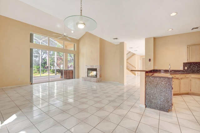 unfurnished living room with light tile patterned flooring, sink, and ceiling fan