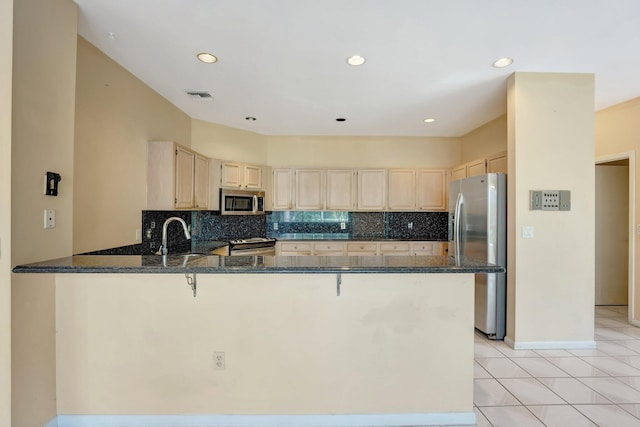 kitchen with decorative backsplash, kitchen peninsula, stainless steel appliances, sink, and light tile patterned floors