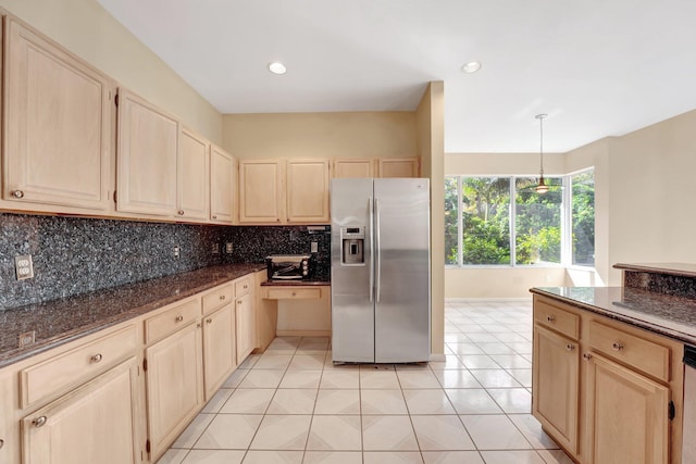 kitchen with backsplash, stainless steel appliances, dark stone counters, pendant lighting, and light tile patterned floors