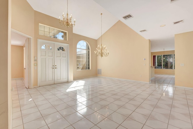 tiled foyer featuring a towering ceiling, a notable chandelier, and a healthy amount of sunlight