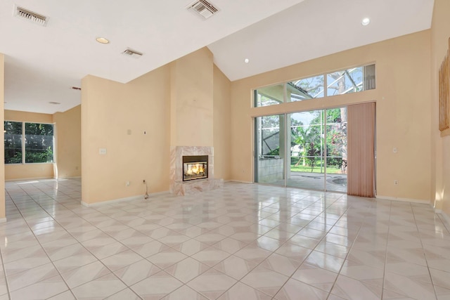 unfurnished living room with high vaulted ceiling, a fireplace, light tile patterned floors, and plenty of natural light