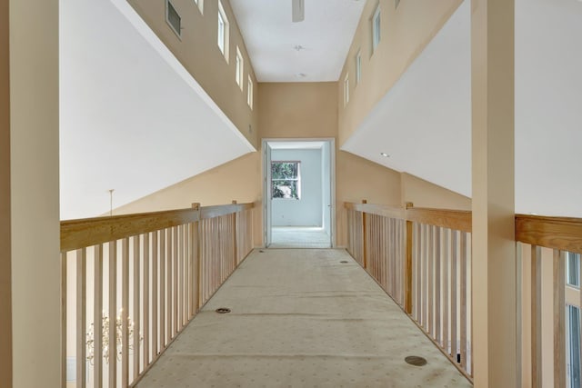 corridor featuring a high ceiling and light colored carpet