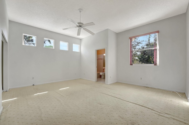 interior space with ensuite bathroom, multiple windows, a textured ceiling, and ceiling fan