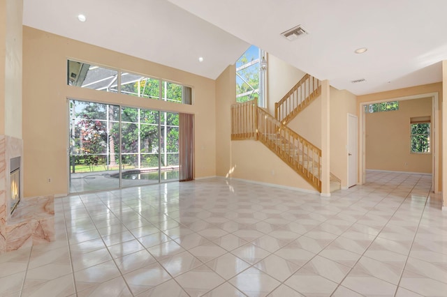 unfurnished living room featuring high vaulted ceiling, a fireplace, and light tile patterned floors