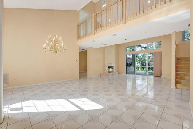 spare room featuring a notable chandelier, a towering ceiling, and light tile patterned floors