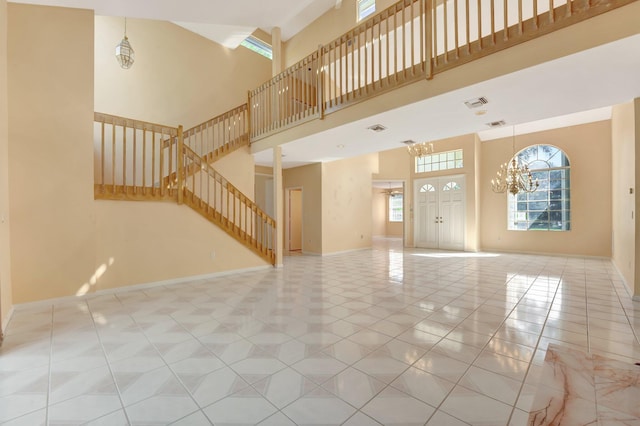 unfurnished living room with a towering ceiling, light tile patterned floors, and a chandelier