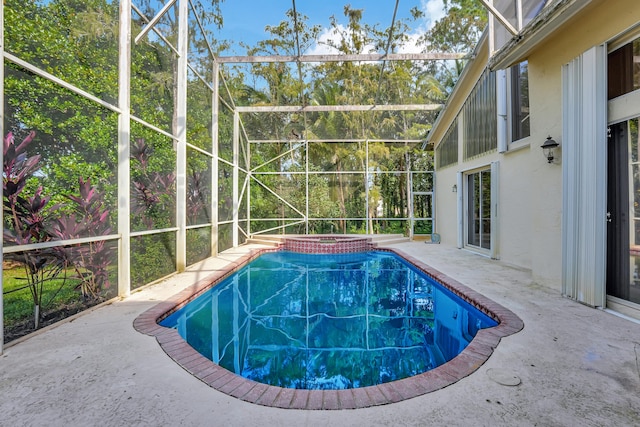 view of pool featuring an in ground hot tub, a patio area, and glass enclosure