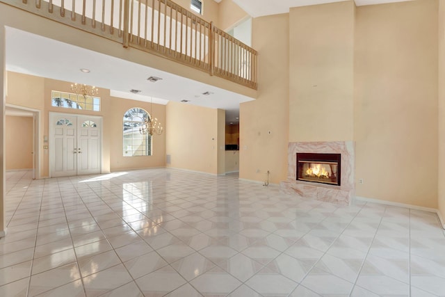 unfurnished living room with light tile patterned flooring, a high ceiling, a fireplace, and an inviting chandelier