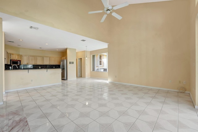 unfurnished living room featuring sink, high vaulted ceiling, and ceiling fan