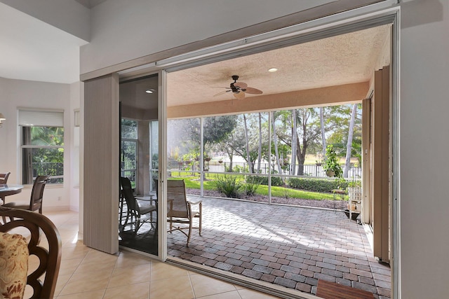 doorway to outside featuring light tile patterned flooring, a textured ceiling, and ceiling fan