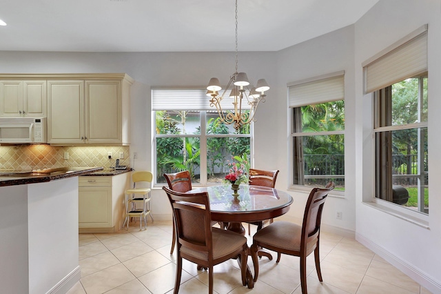 tiled dining area with a chandelier and a healthy amount of sunlight