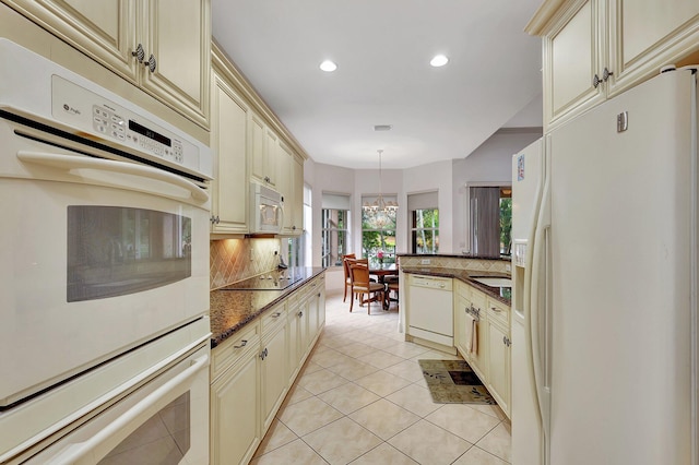 kitchen featuring backsplash, decorative light fixtures, cream cabinets, and white appliances