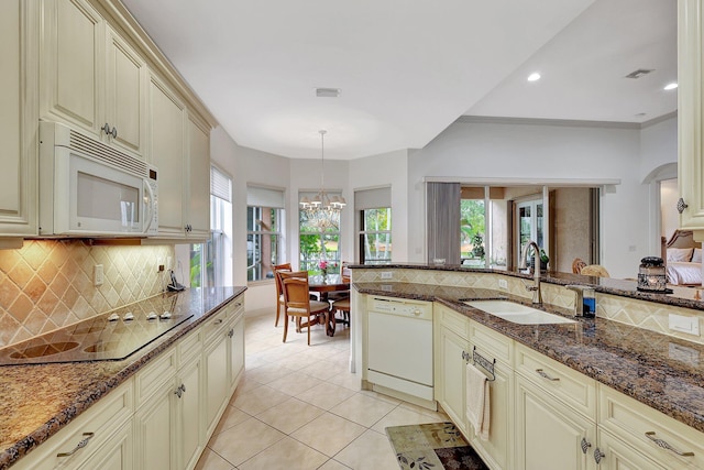 kitchen featuring sink, hanging light fixtures, cream cabinetry, and white appliances