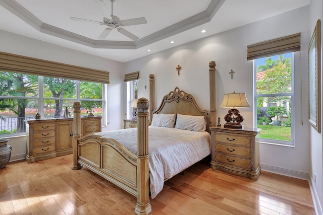 bedroom featuring light hardwood / wood-style flooring, ornamental molding, a tray ceiling, and ceiling fan