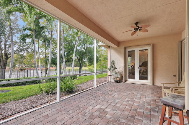 unfurnished sunroom with a water view and ceiling fan