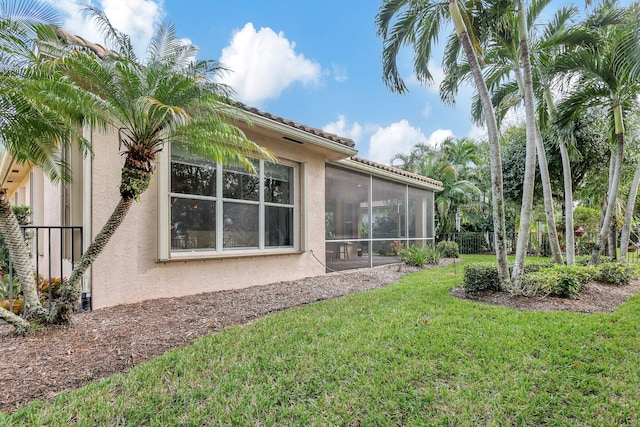 exterior space with a sunroom and a lawn