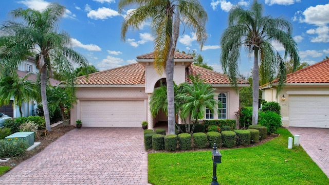 mediterranean / spanish house featuring a front yard and a garage