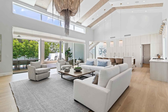 living room featuring light hardwood / wood-style flooring, beam ceiling, high vaulted ceiling, and a wealth of natural light