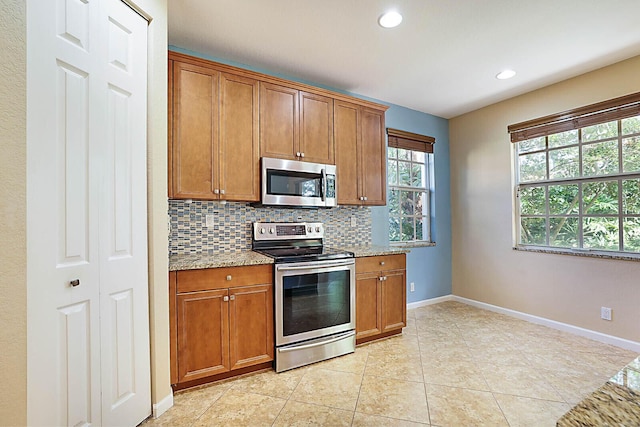 kitchen featuring light stone counters, light tile patterned flooring, stainless steel appliances, and tasteful backsplash