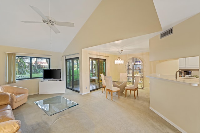 living room featuring light colored carpet, high vaulted ceiling, and ceiling fan with notable chandelier