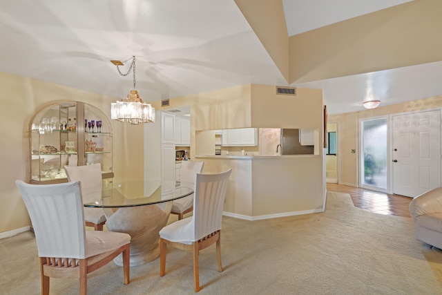 dining room with lofted ceiling, a chandelier, and light colored carpet