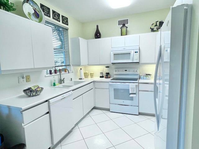 kitchen with white cabinetry, sink, light tile patterned floors, and white appliances