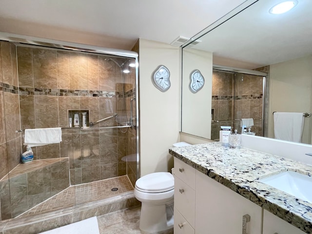 bathroom featuring a shower with door, vanity, and toilet