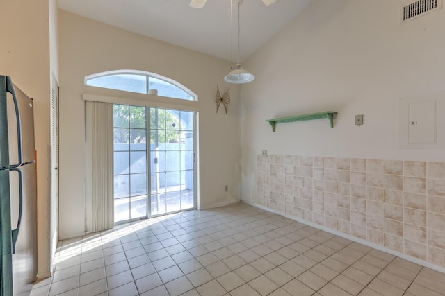 tiled empty room with electric panel and high vaulted ceiling