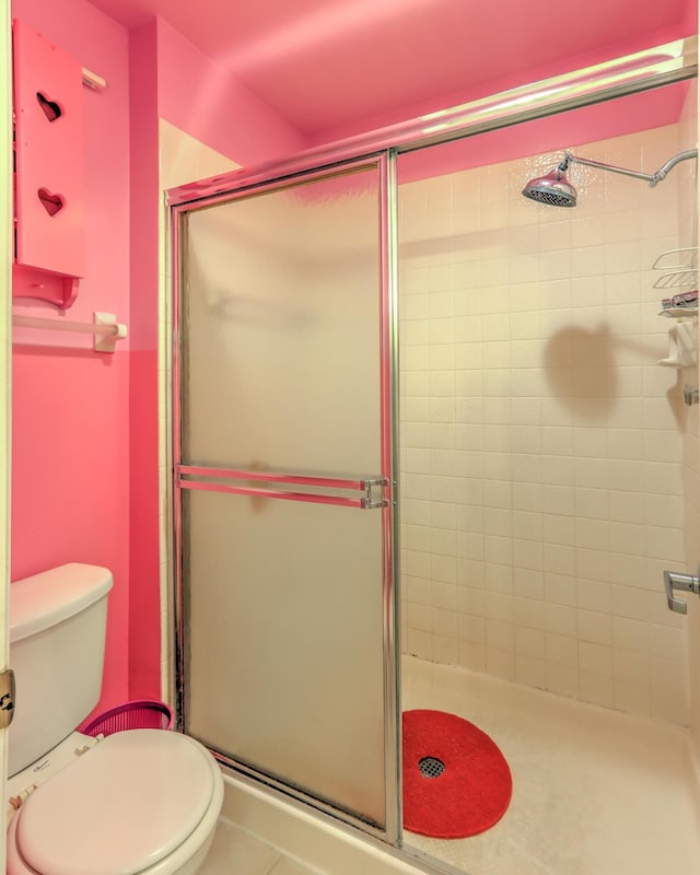 bathroom featuring toilet, tile patterned flooring, and a shower with door