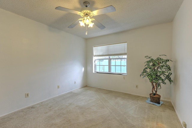 spare room with ceiling fan, light carpet, and a textured ceiling