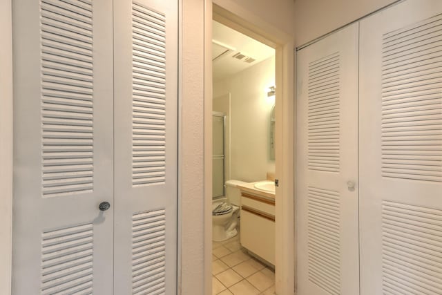 bathroom featuring tile patterned flooring, vanity, walk in shower, and toilet