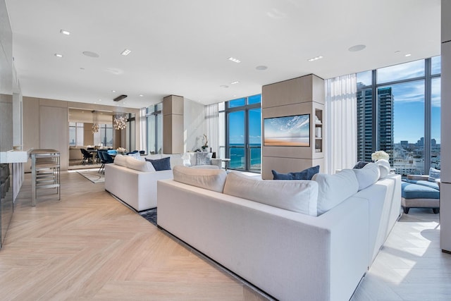 living room with an inviting chandelier, light parquet flooring, expansive windows, and a healthy amount of sunlight