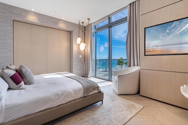 bedroom with a water view, light parquet floors, and access to outside