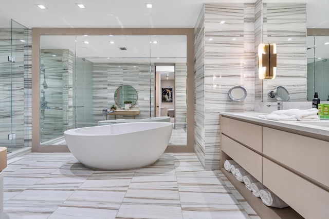 bathroom with tile walls, vanity, and shower with separate bathtub