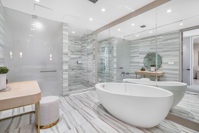 bathroom featuring vanity, independent shower and bath, and tile walls