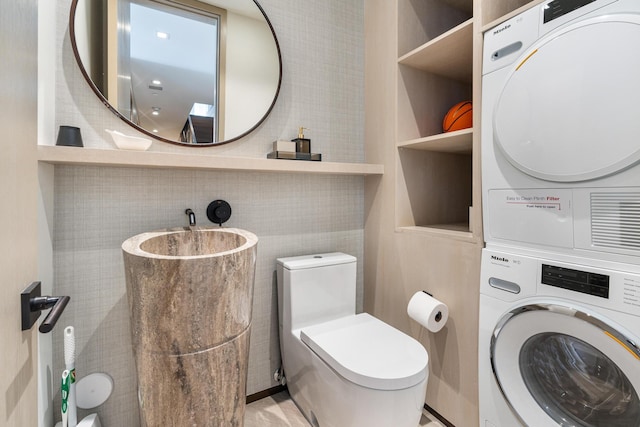 bathroom with toilet and stacked washer and clothes dryer